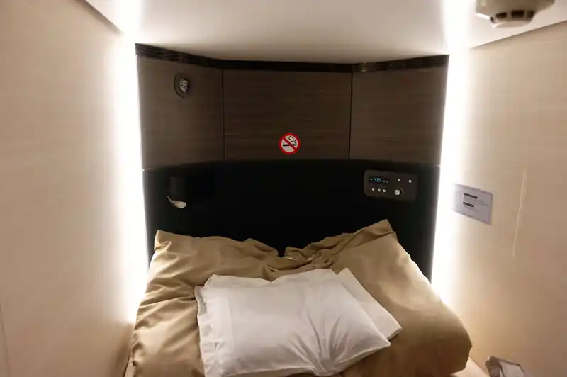 肝心のカプセルホテルの中はこんな感じ。
シーツと枕、敷布団がおいてある。
敷布団はなくても寝れるような感じのマットが敷いてあるが、マット直で寝てると汗で蒸れて不快感MAX。

コンセントが使えてスマフォとかの充電が出来るのが嬉しいところ。明かりは入口のところで消すか、時計のあるパネルのところにボタンがあって消せる。

なお、掛け布団はなし。枕もだいぶ薄くて私にはあわなかったので、テント泊で使ってるエア枕持ってくれば良かったかな、と思う。（持っていこうと思っていたんだけど、忘れてた）
富士山みはらしだと、大部屋に寝る感じになる模様。これはこれでありだと思うけど、自分が寝てる間に他の人が活動しだすと気になりそう。
カプセルホテルだと、入口のスクリーンを下ろしたらほとんど個室みたいな感じなので、居心地は良い。