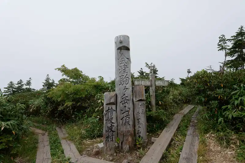 少しばかり登ると会津駒ケ岳山頂に到着。
よく見る山頂標だが、ここで鋭角に曲がっており、右側に行くと中門岳となる。