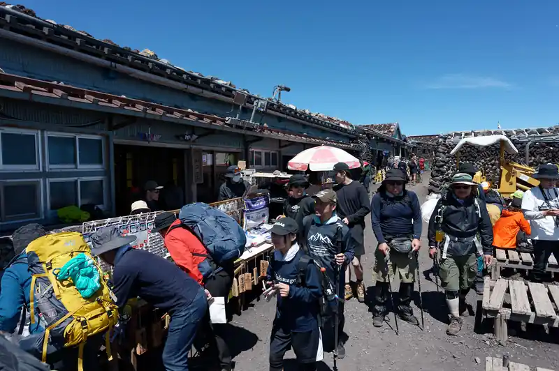 山頂の小屋前は大勢の登山者でごった返している。
ベンチに座って休憩する人、カップ麺やおにぎりを食べる人、気分が悪いのかそういう趣味なのか仰向けに寝ている人、いろいろ。