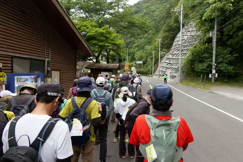 流石に30kmコース参加者は、並々ならぬ人が多い。大半の人が登山好きか、歩くのが好きな人だと思われる。
使用している装備が登山装備らしきものが多く見られ、中にはハイドレーションシステムや、トレラン用のザックを使用している人も多い。

かくいう私も、服装、装備類はほとんど山を歩きに行くときと同じ格好である。唯一違うのは靴くらい。流石に舗装路を、いつも山で履いているハイカットの登山靴では疲れると思い、ジョギングで履いているスニーカーにしたのだが、若干靴のサイズが小さめで、中盤以降で足が傷んで良くなかったかもしれない。

7時30分ごろにスタートし、コース通りに歩いていく。先頭集団はかなりのハイペースだ。名栗湖を一周する頃には、先頭集団は見えなくなっていた。