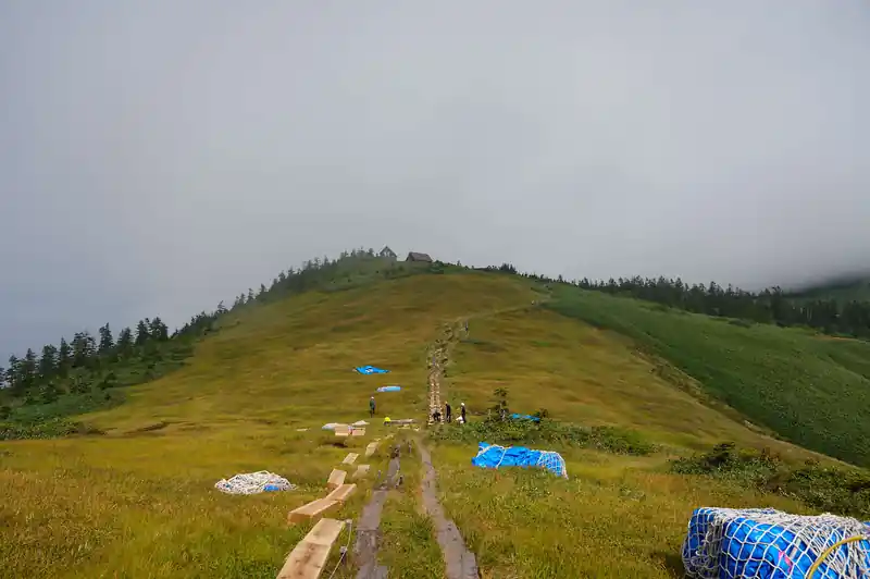修理中の木道とその先に、駒の家の屋根が見える。
ようやくここまで来たか、と一安心。

しかし木道の修繕作業をされている作業員の方たちは毎日登って来ているのだろうか…？