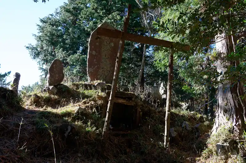 山頂標の近くに、今にも崩れそうな木で出来た鳥居らしきものと、石標。